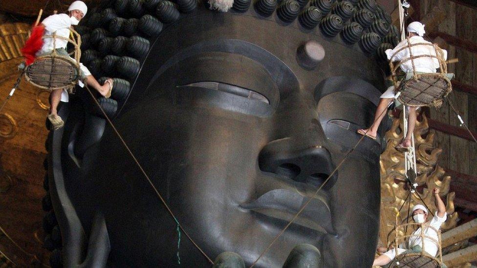monks clean a Buddha