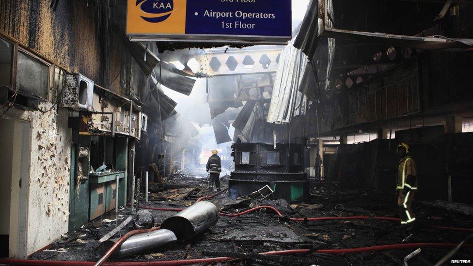 Fire fighters walk amid debris from a fire at the Jomo Kenyatta International Airport in Kenya"s capital Nairobi 7 August 2013.