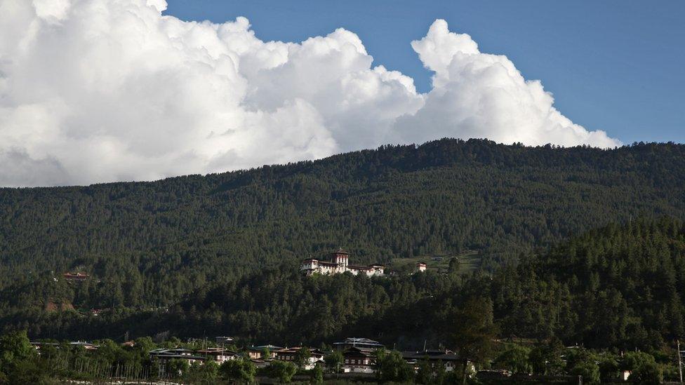 A fortified settlement on a forested hill.