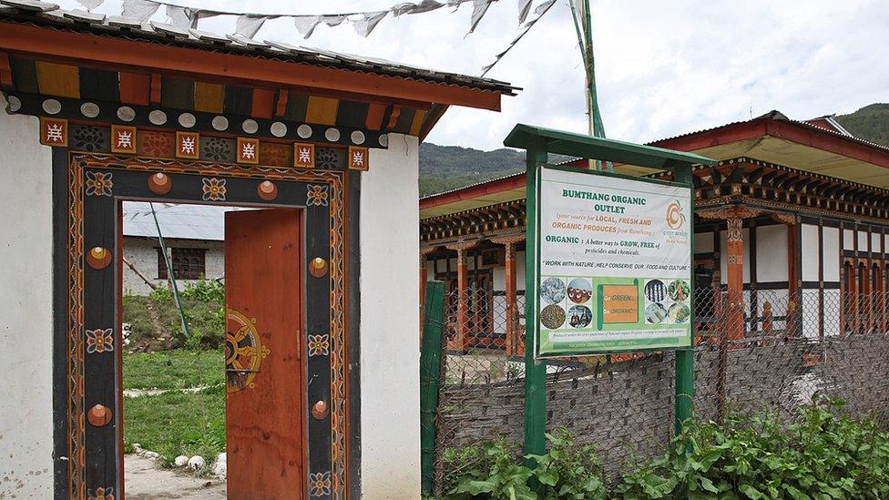 Entrance sign of Bumthang farm shop with prayer flags.