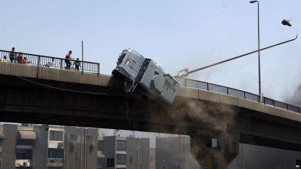 A police vehicle is pushed off of the 6th of October bridge by protesters close to the largest sit-in by supporters of ousted Islamist President Mohammed Morsi in the eastern Nasr City district of Cairo, Egypt, Wednesday, 14 August 2013