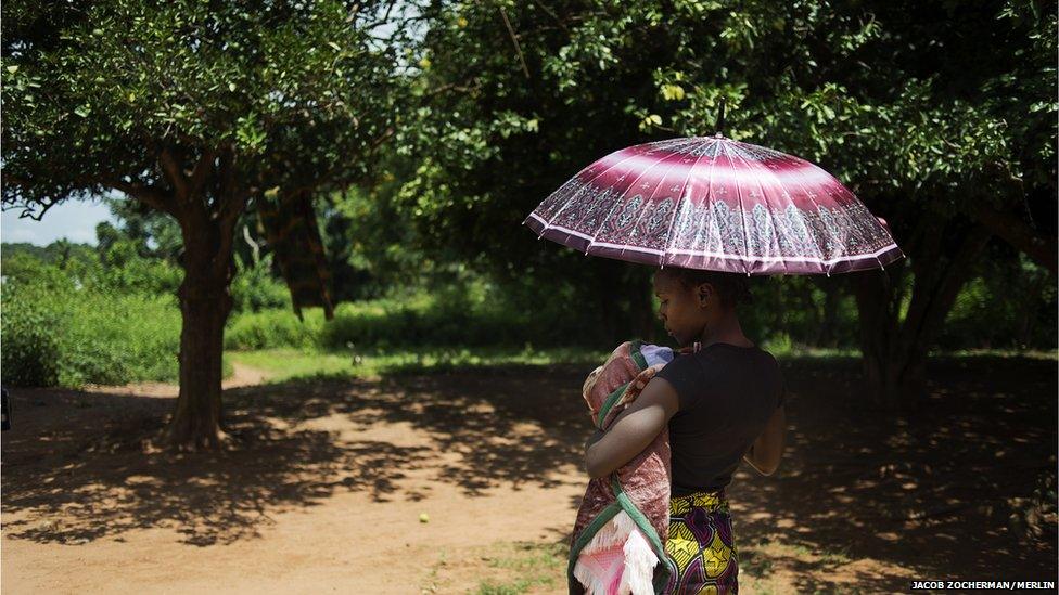 Chimene Kpakanale with her new baby sheltering under an umbrella in Obo, Central African Republic