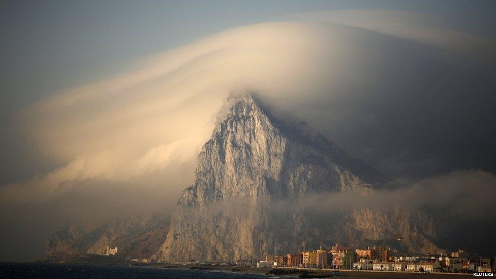 A cloud partially covers the tip of the Rock of the British territory of Gibraltar at sunrise