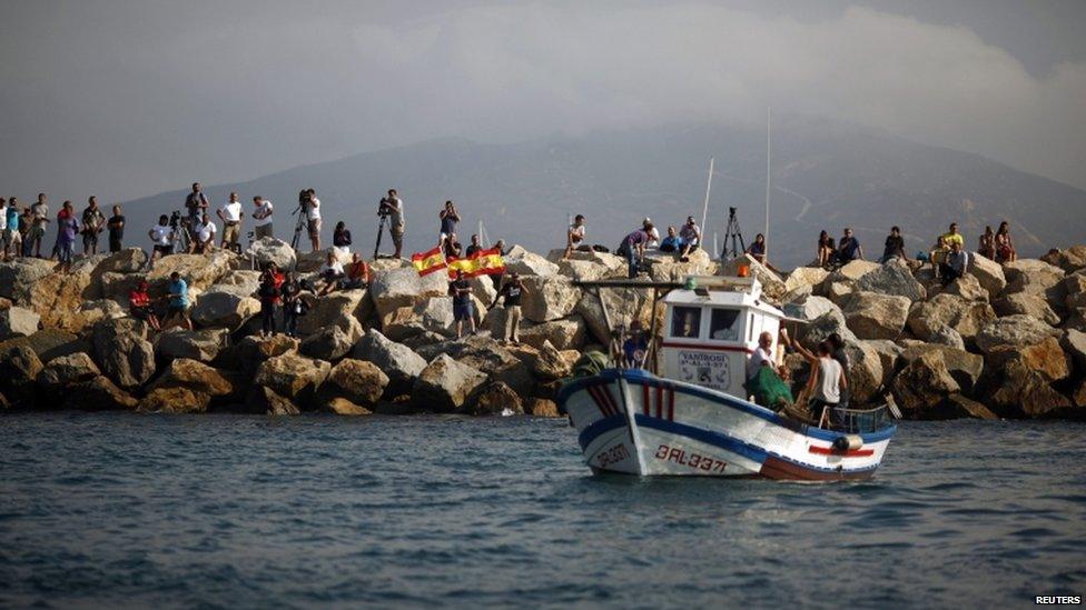 Men wave Spanish national flags during a protest by Spanish fishermen at the site where an artificial reef was built by Gibraltar with concrete blocks