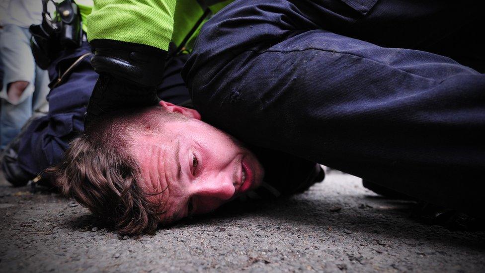 Police officer kneeling on man's head