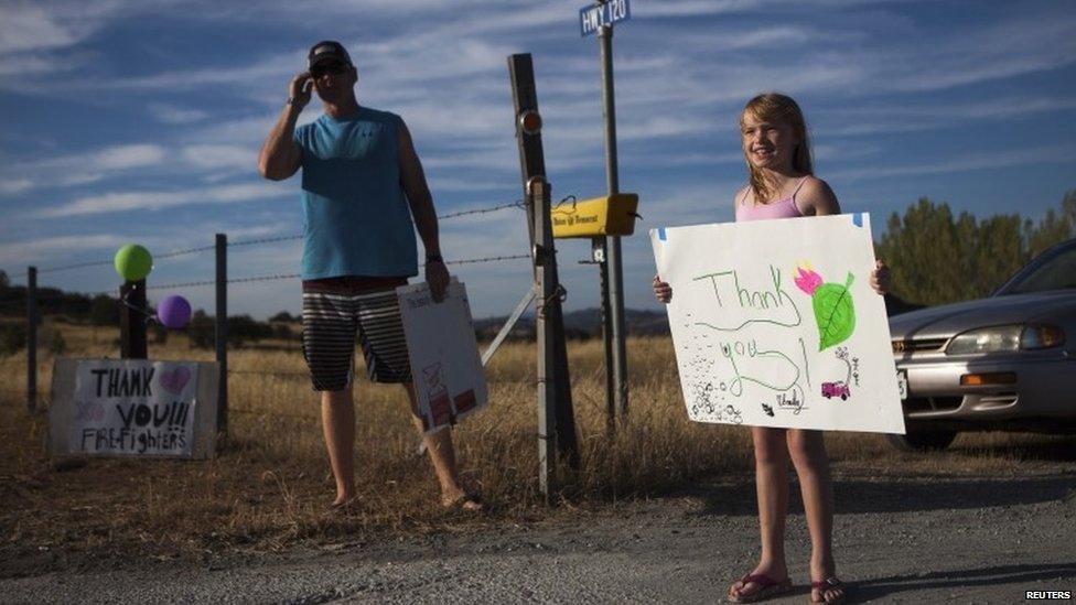 A little girl holds a sign saying "Thank you" after evacuating her home in Groveland, California on 24 August 2013