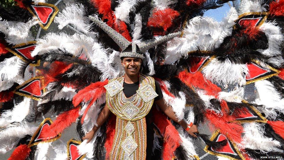 Man in large read and black feather costume