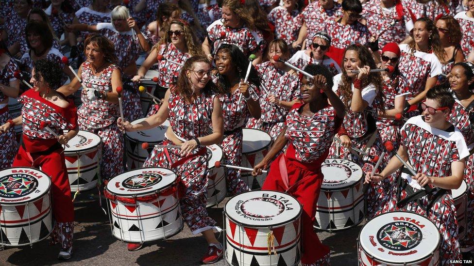 Drummers perform as part of Notting Hill Carnival. They are dressed in bright matching outfits.