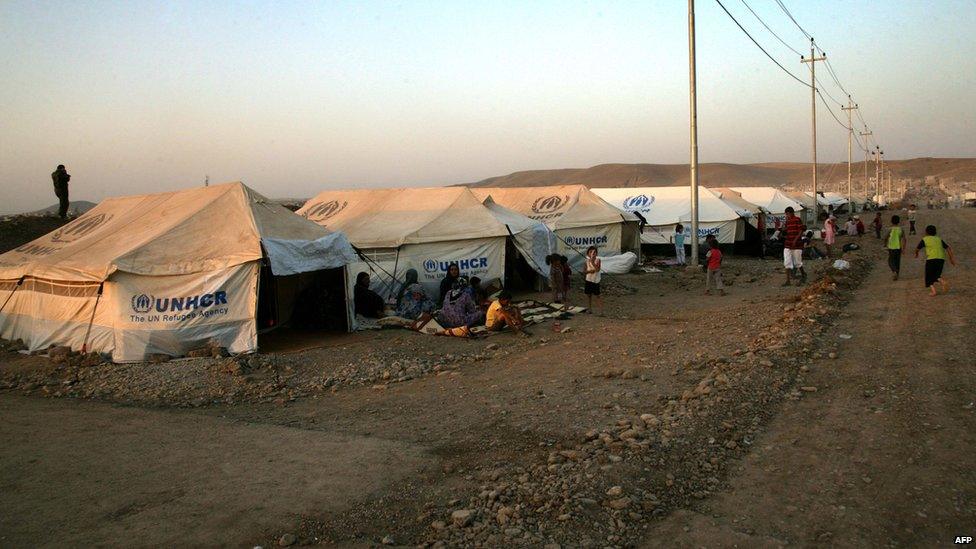 Picture taken on 27 August shows Kurd refugees from Syria sitting outside tents provided by the UNHCR at the Quru Gusik refugee camp, east of Arbil