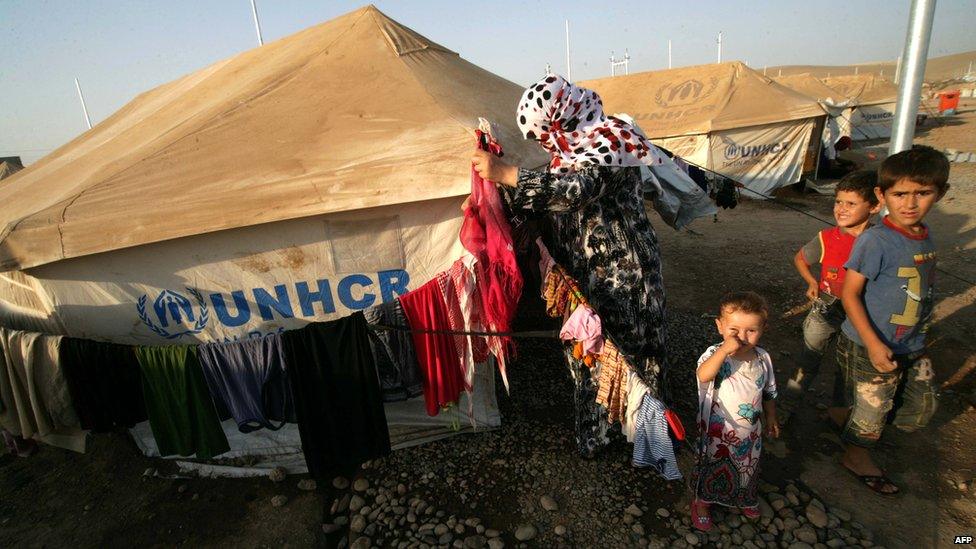 A Syrian-Kurdish refugee woman hangs out her laundry on a clothesline outside a tent provided by the UNHCR at the Quru Gusik refugee camp, east of Arbil