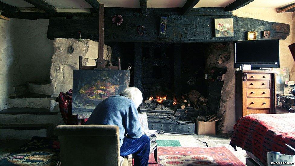 Artist Eleanor Brooks painting in front of her inglenook fire