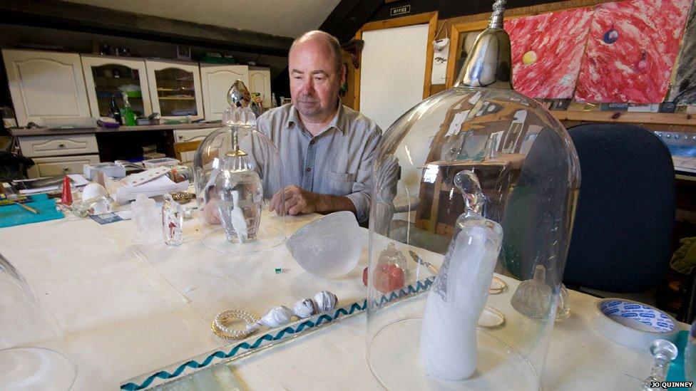 Bill Swann looks at one of his glass creations in his Porthmadog studio