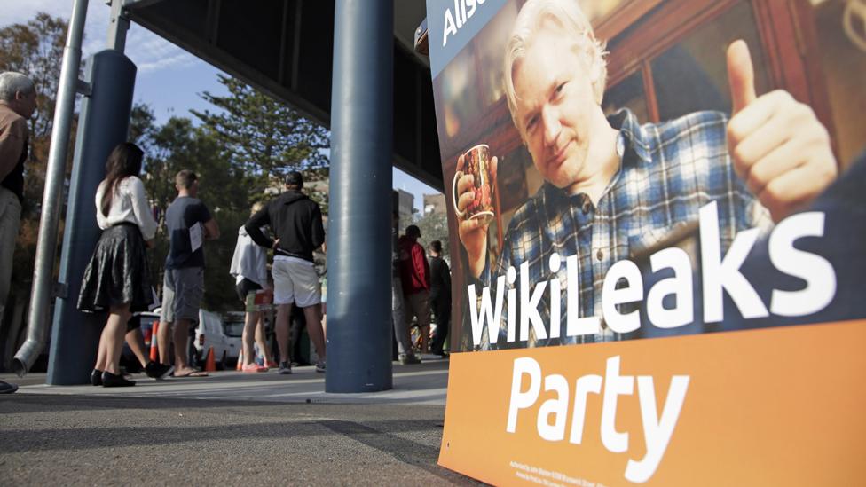 A placard showing WikiLeaks founder Julian Assange is set up as voters line up to fill in their ballots at a polling booth at Bondi Beach in Sydney, Saturday, 7 September