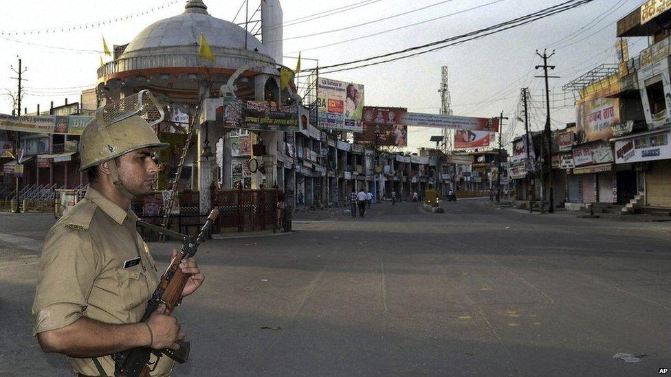 In this Saturday, Sept. 9, 2013 photo, an Indian policeman stands guard during a curfew hours following riots and clashes between two communities in Muzaffarnagar