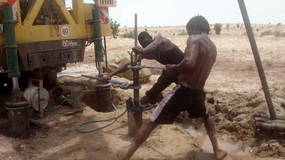 Technicians install a submersible pump in a borehole prior to test pumping, Turkana, Kenya