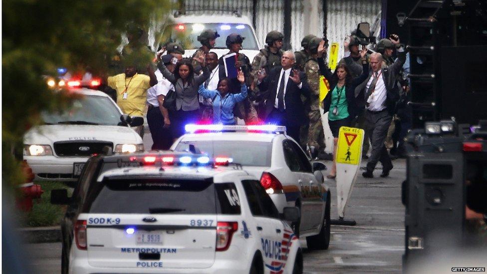 People come out from a building with their hands up after a shooting happened at the Washington Navy Yard (16 September 2013)