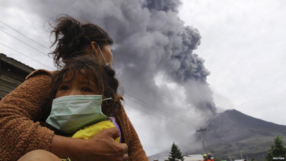 A mother holds her child as Mount Sinabung spews ash and hot lava during an eruption in Perteguhan village in Karo district, Indonesia's north Sumatra province, 17 September, 2013.