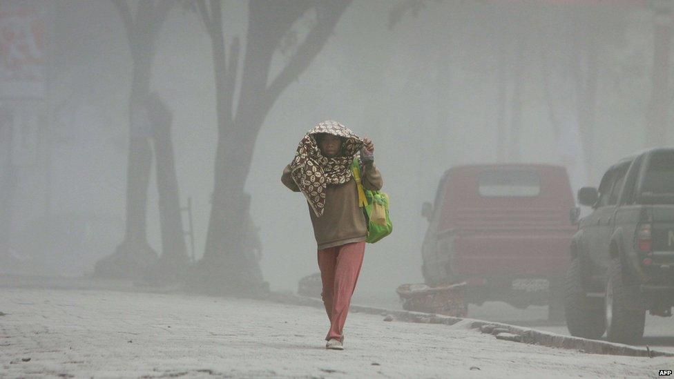 A villager walks under heavy ashfall after a fresh eruption of Mount Sinabung volcano covered Karo district and other areas on 17 September 2013.