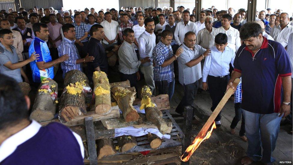 The father (R) of Nehal Vekaria, a 16-year-old female student who was killed during the Westgate Shopping Centre, holds a stick lit with fire at her cremation ceremony in Nairobi (22 September 2013)