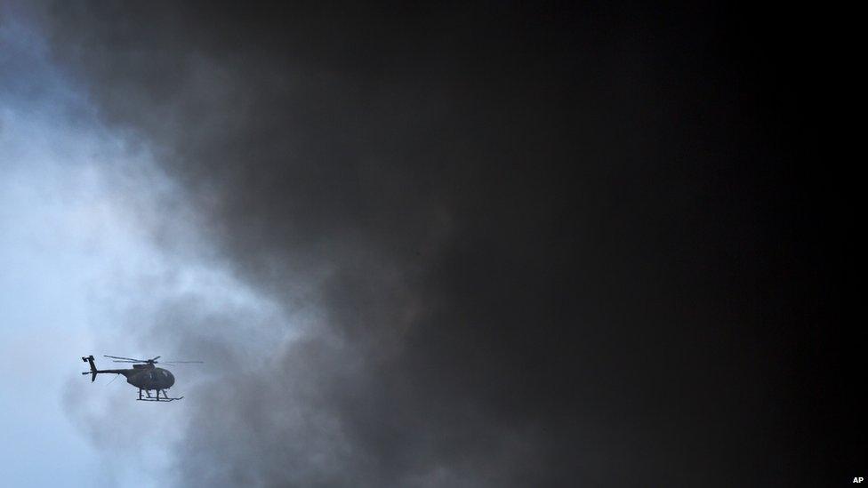 A Kenya Army helicopter flies behind a plume of black smoke billowing from the Westgate Mall, following large explosions and heavy gunfire, in Nairobi, Kenya (September 23)