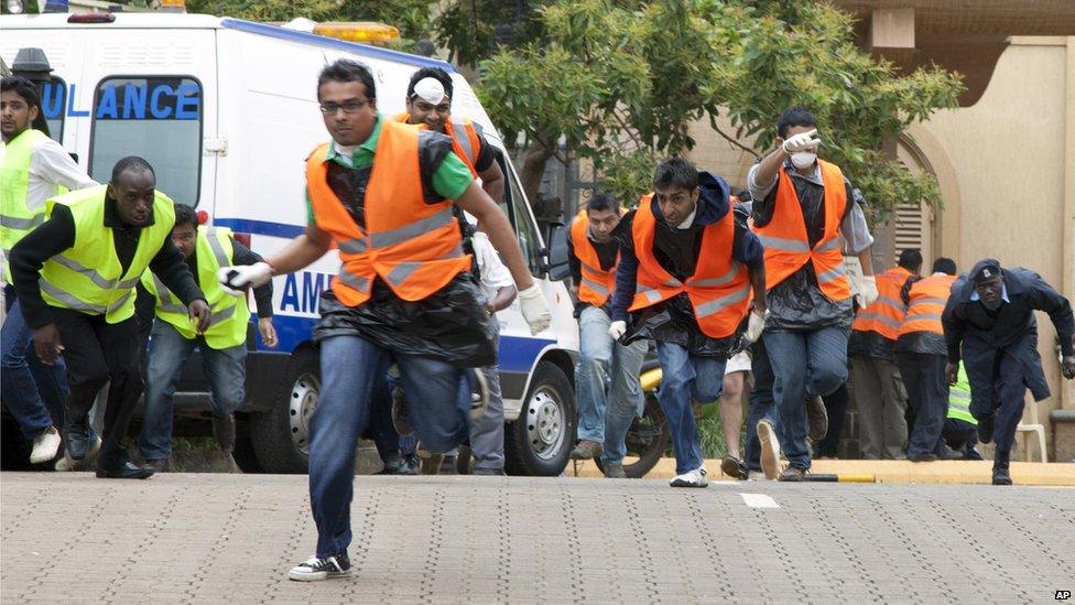 Kenyan Terror Attack: Paramedics run for cover on September 23, 2013 outside the Westgate Mall in Nairobi after heavy shooting started.