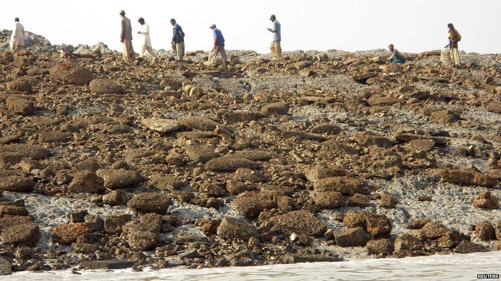 People walk on an island that rose from the sea following an earthquake, off Pakistan's Gwadar coastline in the Arabian Sea