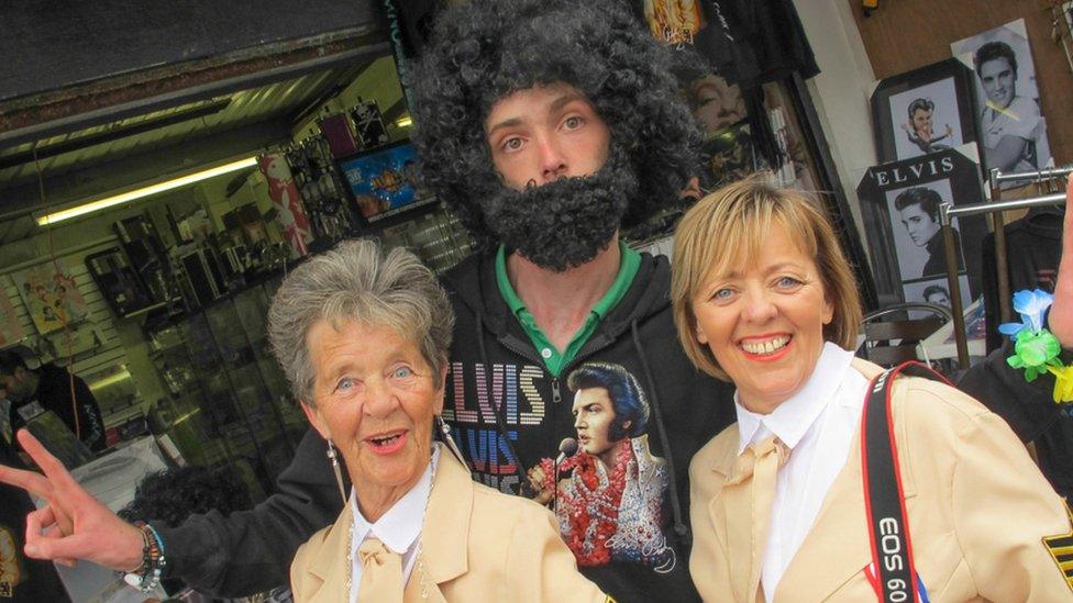 A vendor dressed as Elvis and two visitors to the festival