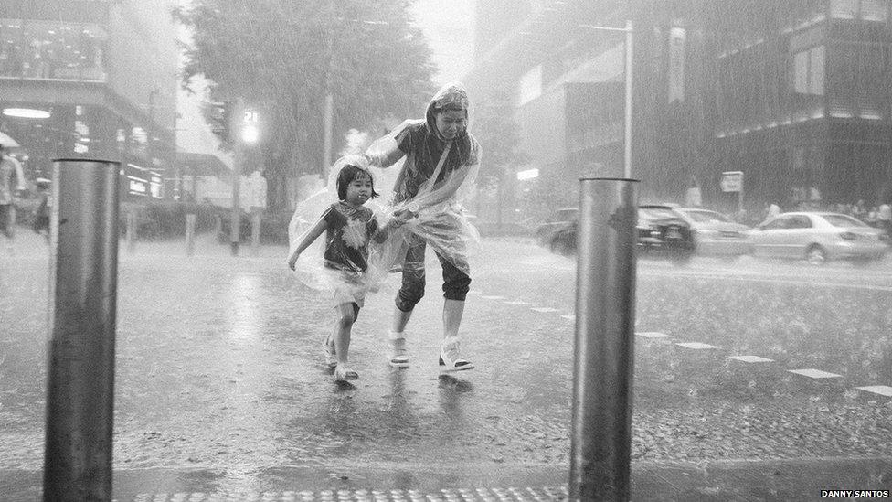 Woman and child walking through torrential rain in Singapore