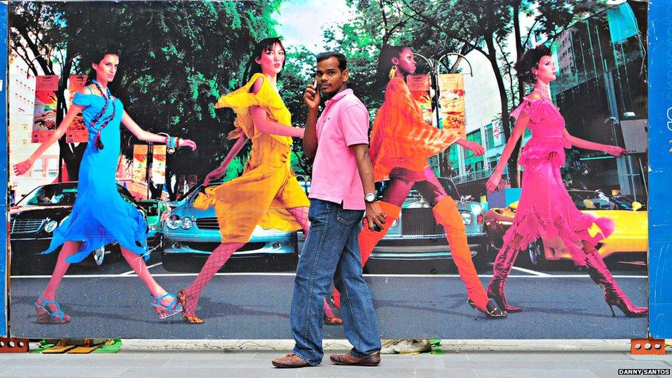 A man walking in front of an advertising billboard.