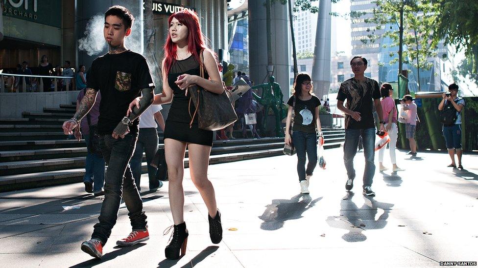 A young couple with tattoos, walk in front of a building