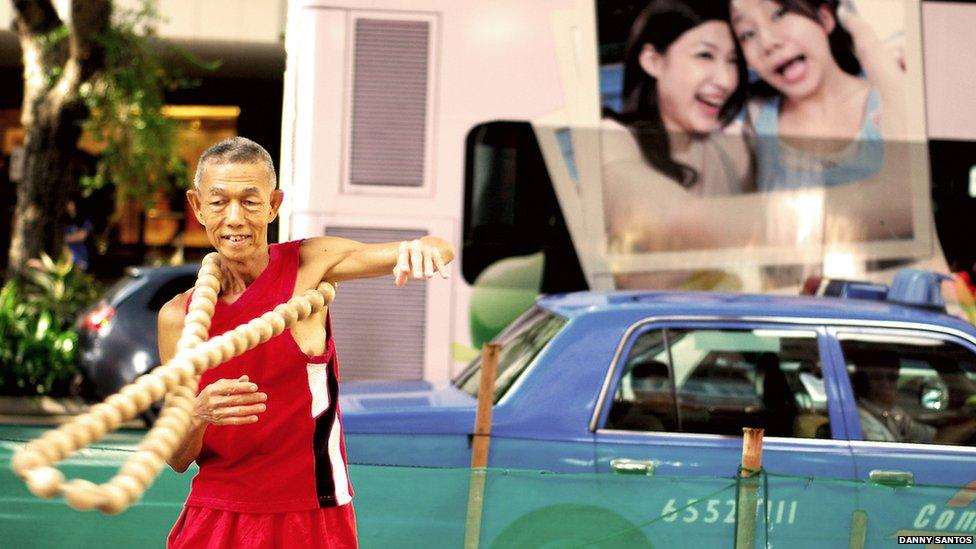 A busker hula hooping giant beads around his body