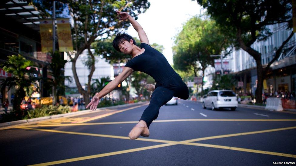 A ballet dancer leaping along one of Singapore's main roads