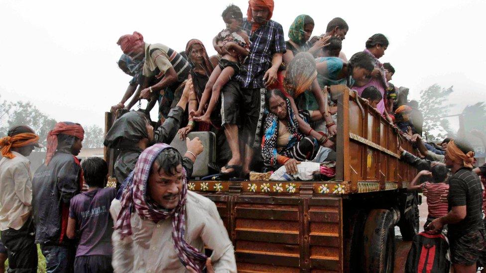 Evacuated Indian villagers get down from a truck at a relief camp as it rains near Berhampur on 12 October 2013