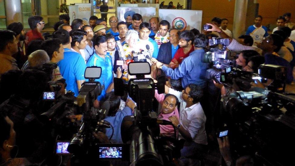 The Queen's Baton arrives amid a media scrum in New Delhi.