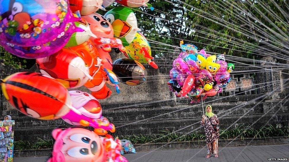 Woman holding colourful balloons outside a monument in Denpasar, Bali