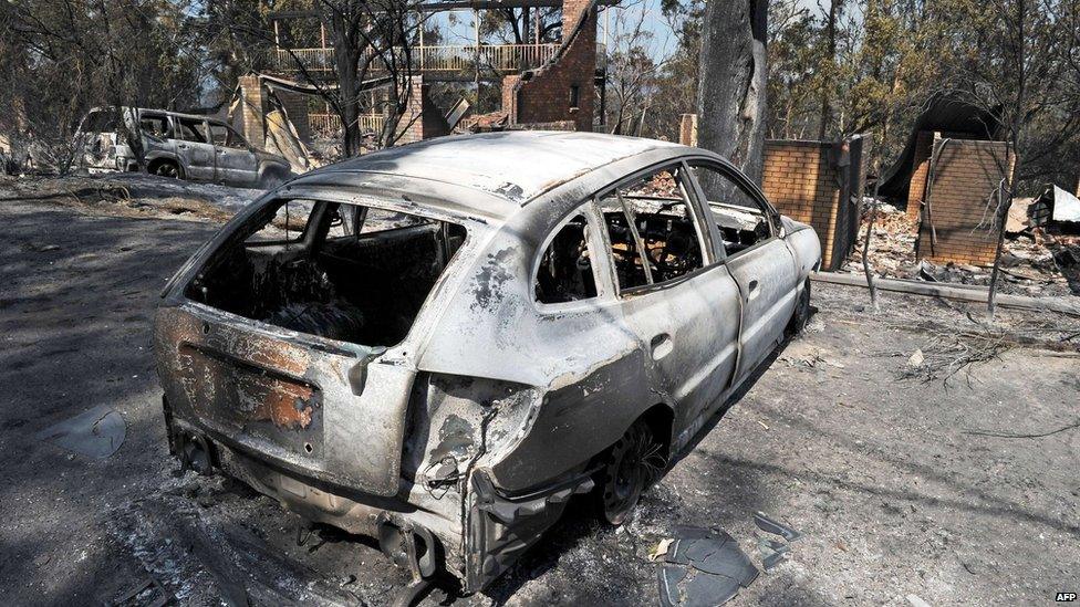 A burnt-out car sits in front of a house destroyed by bushfires in Winmalee in Sydney's Blue Mountains on 18 October 2013