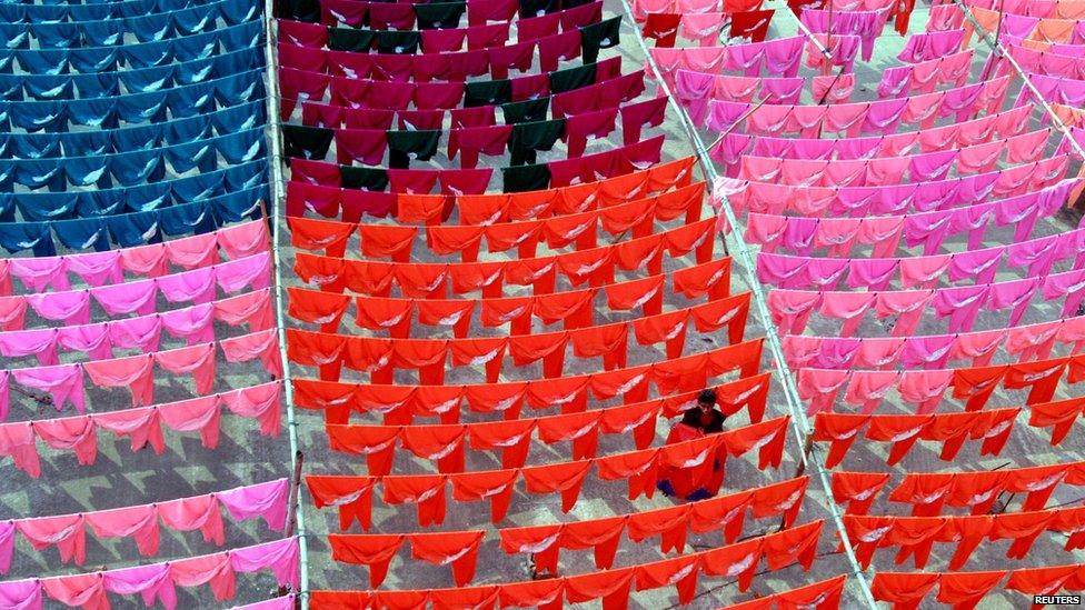 Worker hanging up brightly coloured clothes