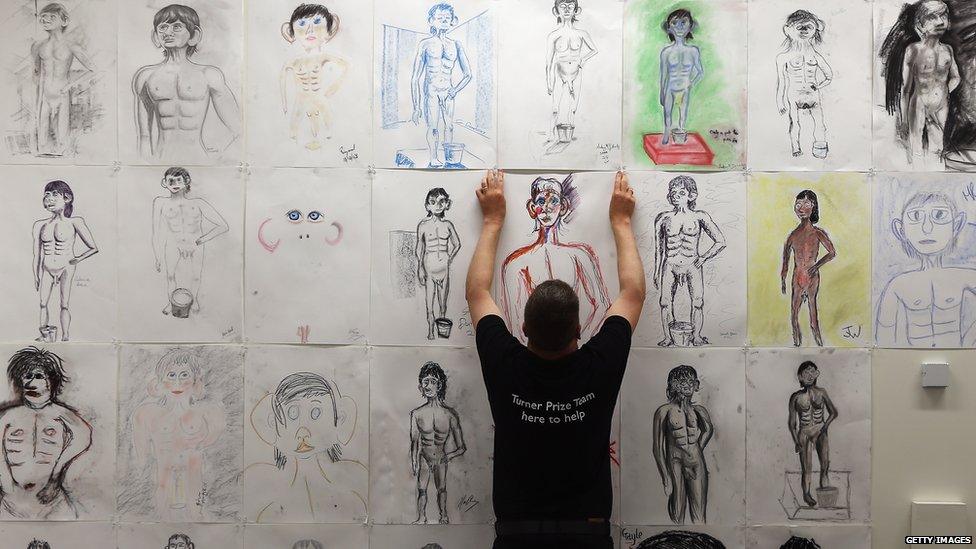 A technician hangs a drawing by a member of the public of Turner Prize-nominated artist David Shrigley's Life Model