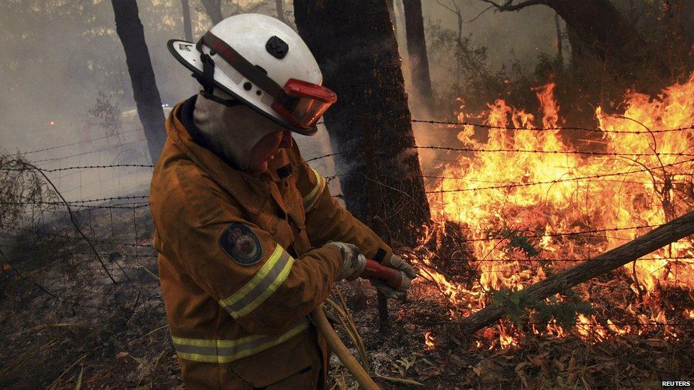 Rural Fire Service firefighter sprays water on to a fire burning a home in the Blue Mountains suburb of Faulconbridge. 22 Oct 2013