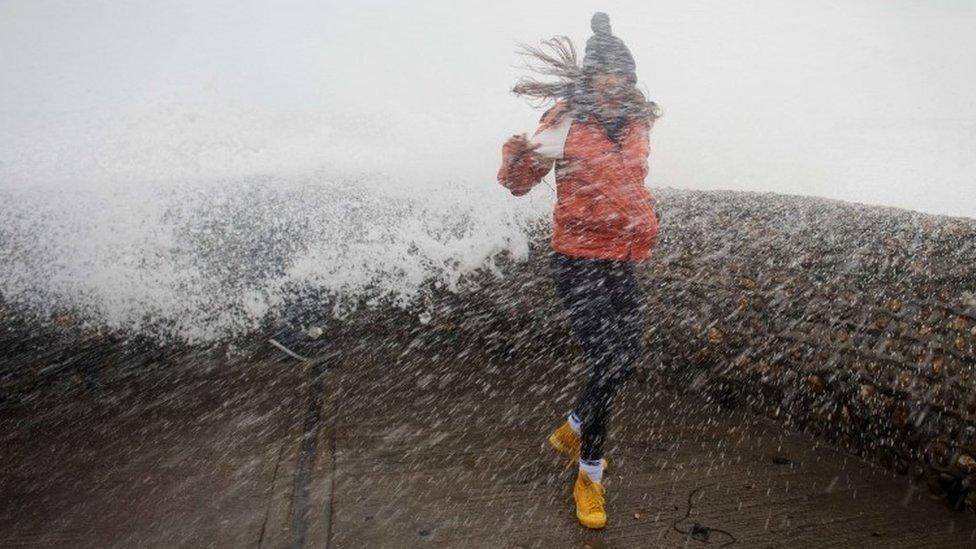 Girl being hit by wave on Brighton seafront