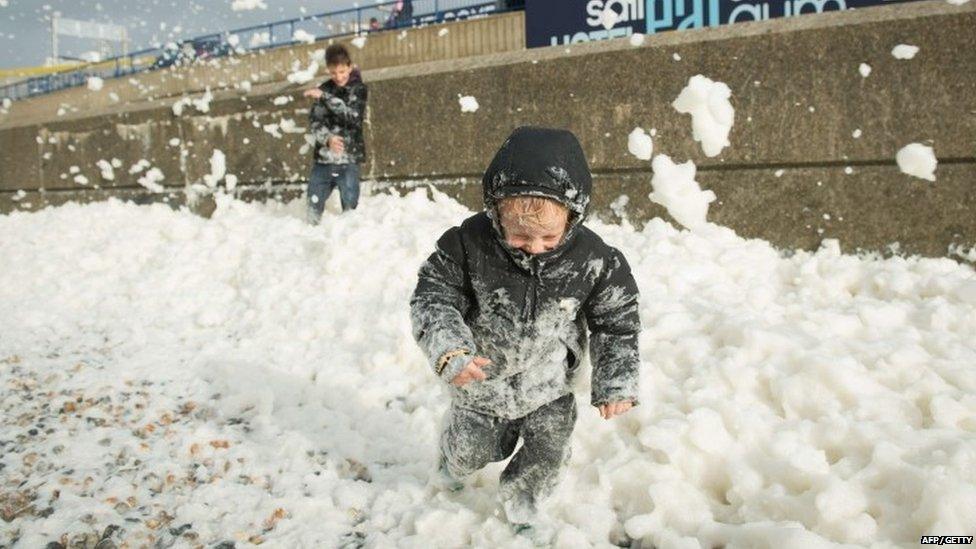 Will Brewer, 4, plays in the foam washed ashore on the Brighton seafront as high winds pick up ahead of an expected storm