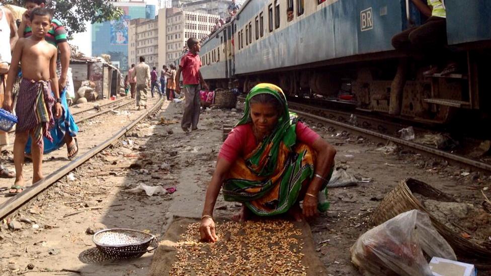 A women prepares food on near the train line in Dkaka.