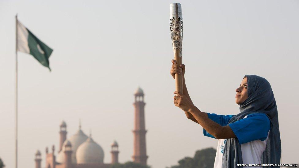 The Queen's Baton is held aloft by Pakistani karate athlete Benish Akbar, with the Badshahi Mosque in the background, in Lahore, Pakistan.