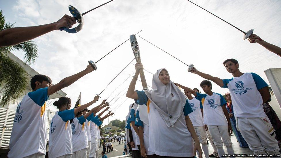 Athletes with fencing foils present a guard of honour for the Queen's Baton in Brunei.