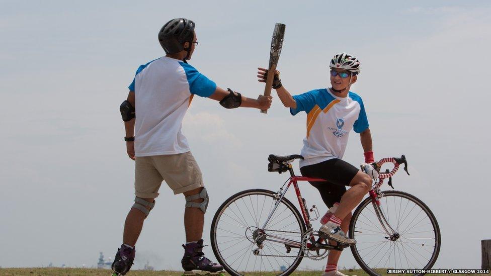 Rollerblader Lim Wu Kai hands over the Queen's Baton to cyclist Kenneth Kang in Singapore.