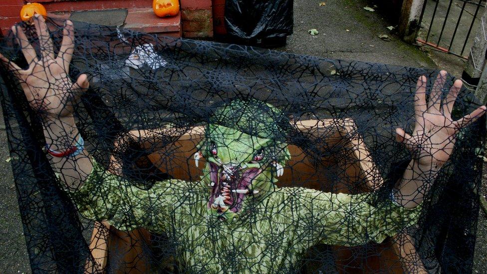 A man dressed in a swamp man costume under a net looking scary