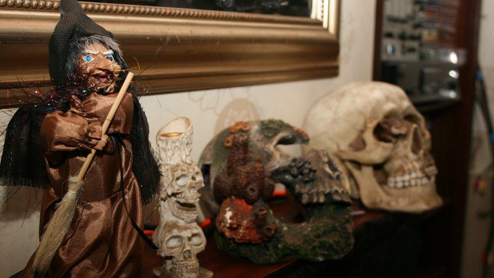 A witch and some skulls on a mantlepiece