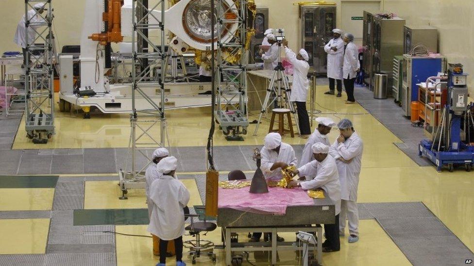 Indian engineers work with their staff next to a pyramid shaped rocket or Liquid Apogee Motor, foreground, to be installed on the Mars orbiter spacecraft, background, at the satellite centre of Indian Space Research Organization (ISRO) in Bangalore