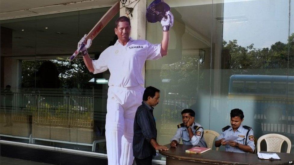 Security men sit beside a cut-out of Tendulkar at the entrance to Eden Gardens, the venue of the first Test match between India and West Indies, in Calcutta