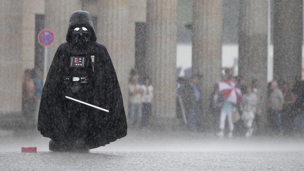 Person in Darth Vader costume standing in rain